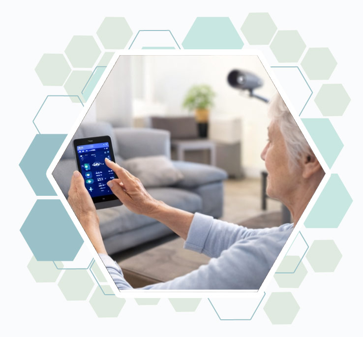 Une senior assise dans son salon utilise une interface domotique sur téléphone portable.