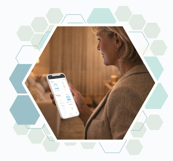 Une dame senior interagit avec un écran de contrôle domotique mural.