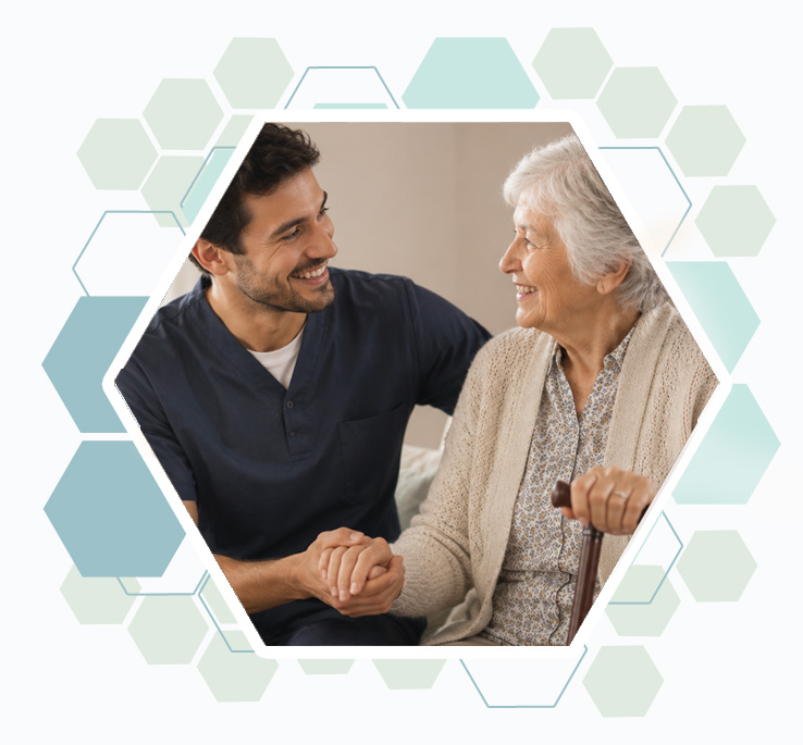 Un aide a domicile tient la main d'une senior âgée qui s'appuie sur une canne, les deux sont souriant.